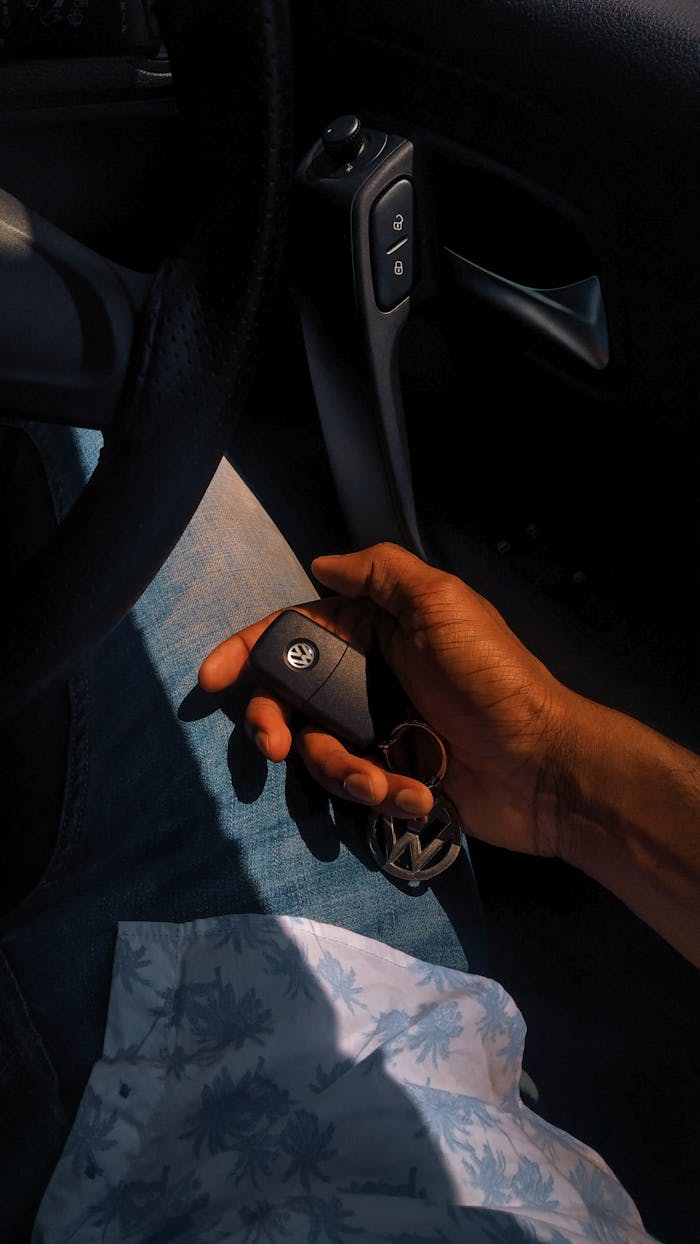 about-us-01 Close-up of a hand holding a car key inside a vehicle, showcasing automotive lifestyle.