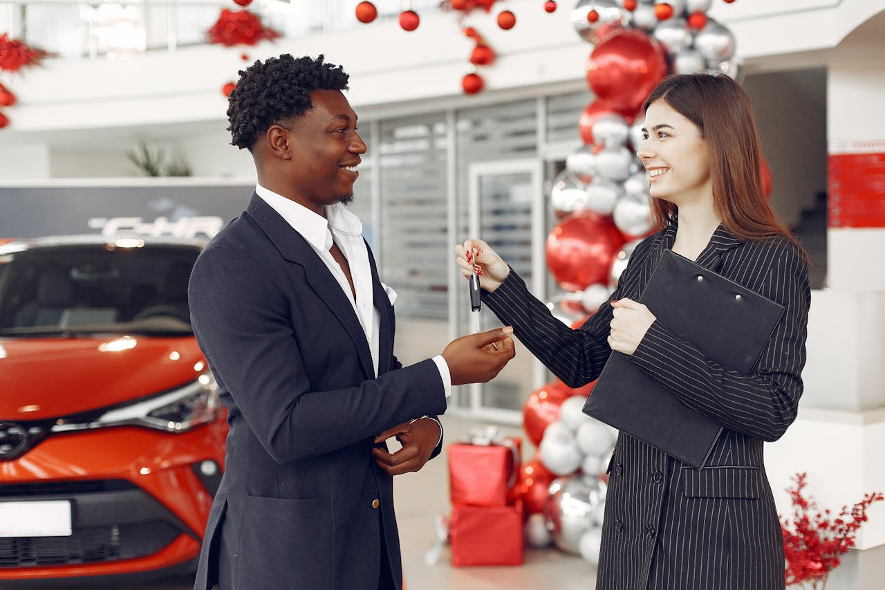 heros-img A car dealer handing over keys to a satisfied customer at a decorated dealership.